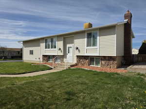 Raised ranch featuring a chimney and stone siding