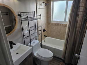 Bathroom featuring shower / bath combo with shower curtain, vanity, and dark wood finished floors