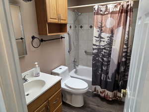 Full bathroom with vanity, shower / tub combo with curtain, and dark wood-style floors