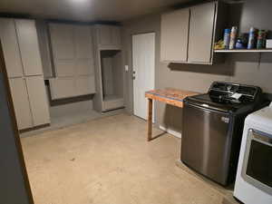 Laundry room featuring concrete flooring, washing machine and clothes dryer, and cabinet space