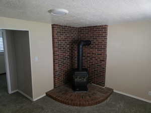 Detailed view of a wood stove, carpet, and a textured ceiling