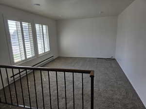 Carpeted spare room featuring a baseboard heating unit and a baseboard radiator