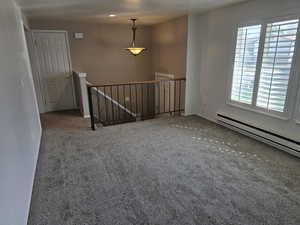 Carpeted spare room with baseboard heating and baseboards