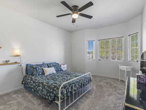 Carpeted bedroom featuring baseboards and a ceiling fan