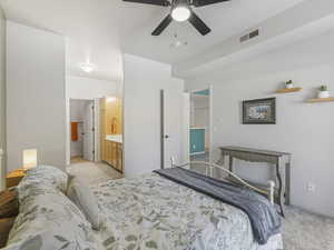 Bedroom featuring light carpet, ceiling fan, and connected bathroom