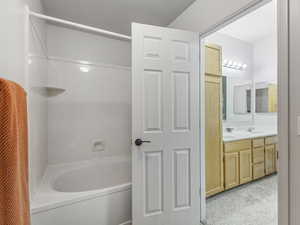 Bathroom featuring double vanity, bathing tub / shower combination, and light colored carpet