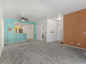 Unfurnished living room featuring ceiling fan and light colored carpet