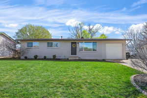 Ranch-style house featuring brick siding, a front yard, an attached garage, and concrete driveway