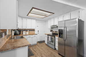Kitchen featuring stainless steel appliances, dark countertops, white cabinetry, and decorative backsplash