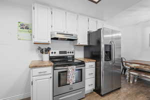 Kitchen with stainless steel appliances, white cabinetry, and dark wood-style flooring