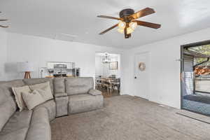 Carpeted living room with a ceiling fan and attic access
