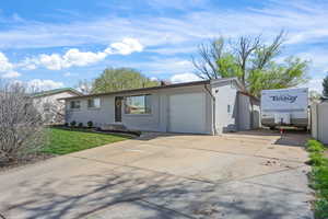 Ranch-style home featuring concrete driveway, an attached garage, brick siding, and a front lawn