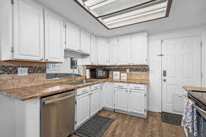 Kitchen featuring white cabinetry, stainless steel appliances, backsplash, and dark wood finished floors