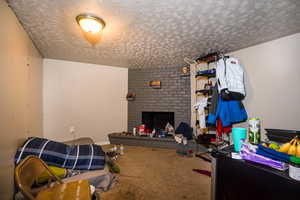 Living area featuring a fireplace, carpet floors, and a textured ceiling