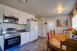 Kitchen with stainless steel appliances, white cabinets, and a textured ceiling