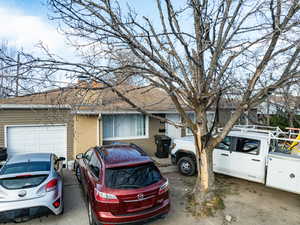 View of front facade featuring brick siding, roof with shingles, a garage, and a chimney