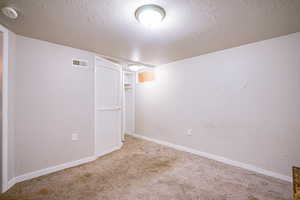 Carpeted spare room with a textured ceiling and a smoke detector