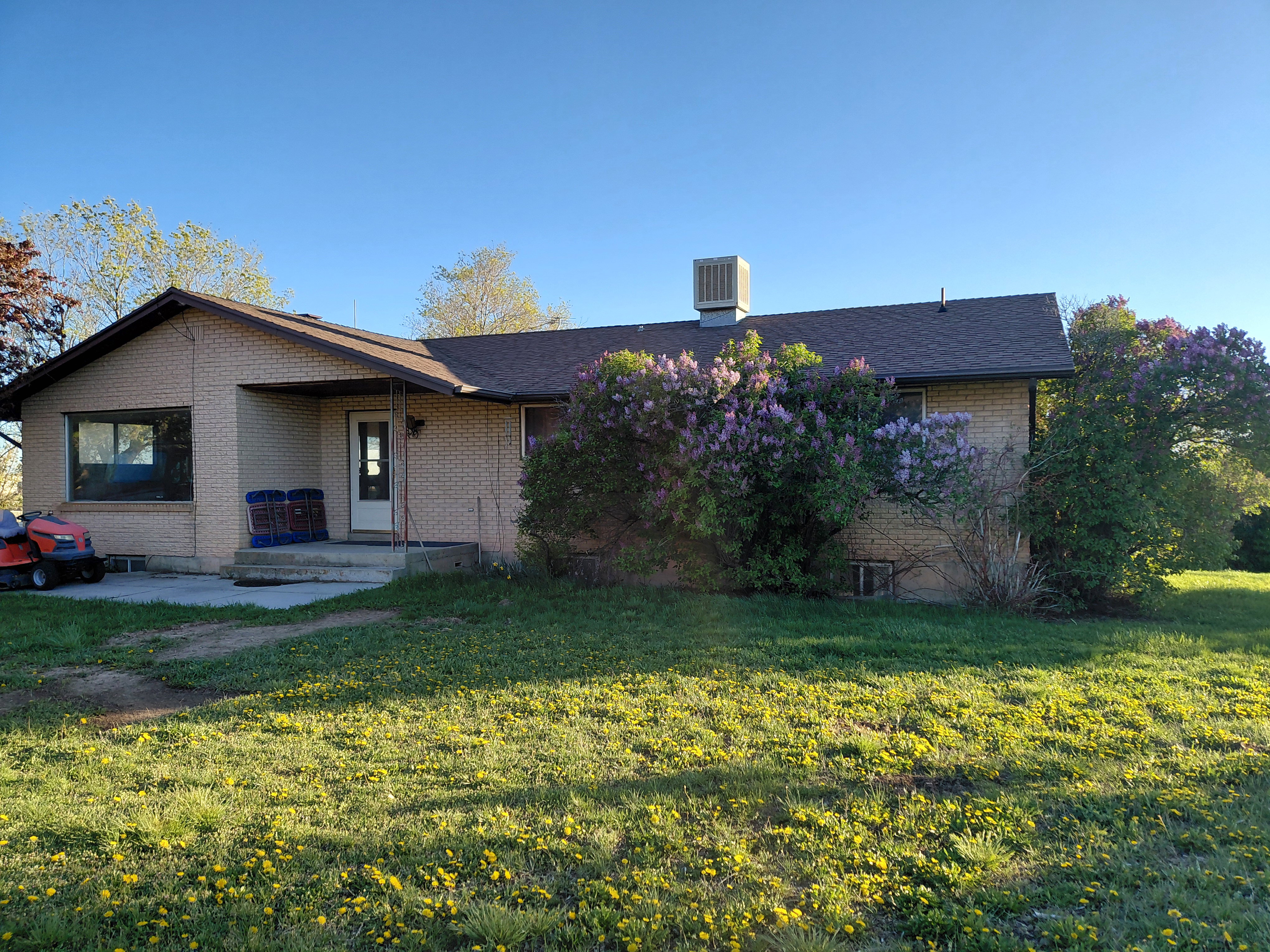 View of front of property featuring brick siding, a front yard, a shingled roof, and a patio area