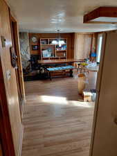 Kitchen and dining area with wooden walls, light wood-type flooring, and a chandelier