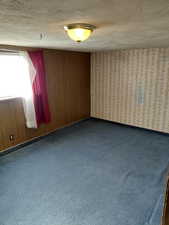 Bedroom with dark carpet and a textured ceiling