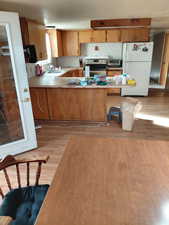 Kitchen featuring light countertops, freestanding refrigerator, a peninsula, stainless steel electric stove, and light wood-type flooring