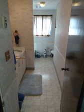 Full bath with wallpapered walls, vanity, and a toilet and tub.