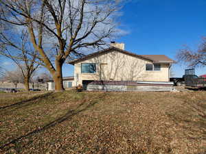 View of east side of property featuring brick siding, a chimney, and a yard