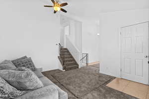 Carpeted living area with ceiling fan and tile patterned floors