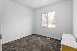 Empty room featuring dark carpet and baseboards