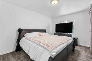 Bedroom featuring dark colored carpet and a textured ceiling