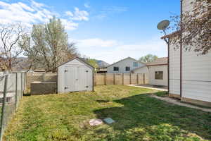 Fenced backyard featuring a shed and a patio area