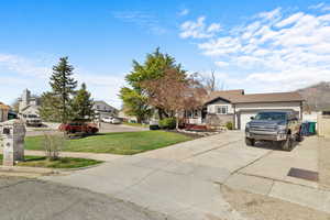 View of front of home with driveway, a front lawn, a garage, and a residential view