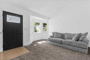 Foyer entrance with dark carpet, vaulted ceiling, and dark tile patterned flooring
