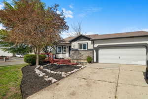 View of front of property featuring concrete driveway, stucco siding, a garage, stone siding, and a deck