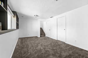 Basement featuring dark colored carpet and a textured ceiling
