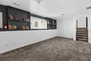 Unfurnished room with dark carpet and a textured ceiling