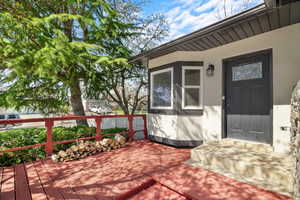 Doorway to property featuring stucco siding and a deck