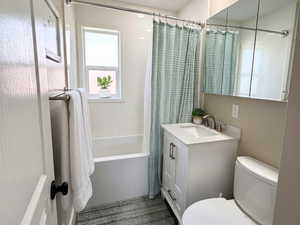 Bathroom featuring vanity, shower/bathtub combination with curtain, dark wood-style tile, and recessed lighting
