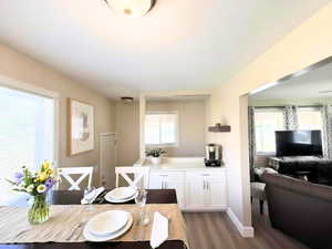 Dining space featuring light wood-style LVP flooring and baseboards with a modern coffee bar and door to backyard.