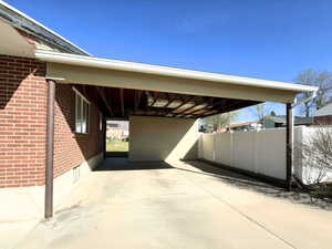 View of parking with an attached carport and concrete driveway & storage shed