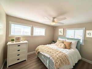 Bedroom 3 with LVP wood-type flooring, multiple windows, and a ceiling fan. enhanced photo staged.
