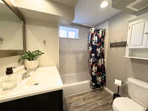 Full Bathroom with vanity, shower / bathtub combination with curtain, and wood finish floors