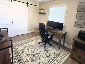 Office/bedroom 2 area featuring a barn door, wood finished LVP floors, and a ceiling fan