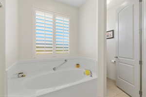 Full bathroom featuring a bath and light tile patterned floors