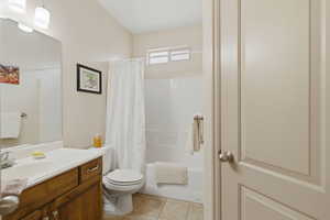 Bathroom with vanity, shower / bath combination with curtain, and light tile patterned floors