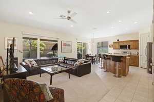 Living room featuring a ceiling fan, light tile patterned flooring, and a chandelier