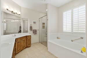 Bathroom featuring double vanity, light tile patterned flooring, a shower stall, and a garden tub