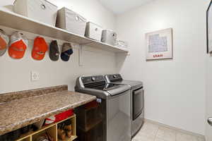 Laundry area featuring washer and clothes dryer and light tile patterned flooring