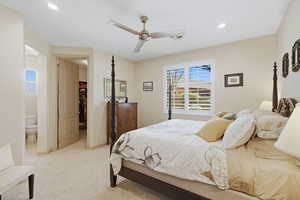 Bedroom featuring a spacious closet, ceiling fan, light colored carpet, recessed lighting, and ensuite bath