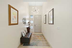Foyer with light tile patterned floors and a chandelier